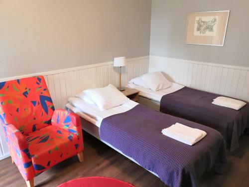 a hotel room with two beds and a chair at Hotelli Messilä in Lahti
