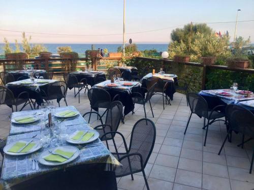 eine Terrasse mit Tischen und Stühlen und Meerblick in der Unterkunft Hotel Jonio in Noto Marina