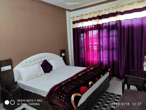 a bedroom with a white bed with purple curtains at THE HIMALAYAS GUEST HOUSE in Dharamshala