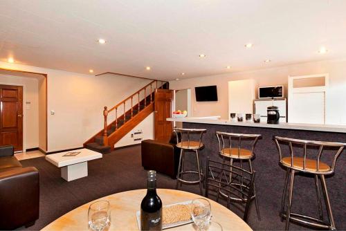 a room with a bar and some chairs and wine bottles at Colonial Inn Motel in Christchurch