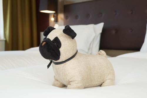 a stuffed pug dog sitting on a bed at Wychwood Park Hotel and Golf Club in Crewe