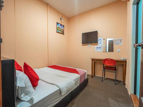 - une chambre avec un lit et un bureau avec une télévision dans l'établissement OYO 89328 Sz Hotel, à Lumut