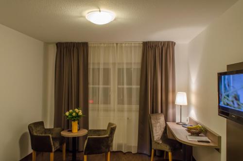 a room with a table and chairs and a television at City Hotel Wiesbaden in Wiesbaden
