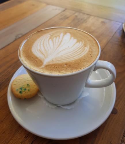 a cup of coffee on a plate with a cookie at Mijn Kitchen Coffee Shop and B&B in Blantyre