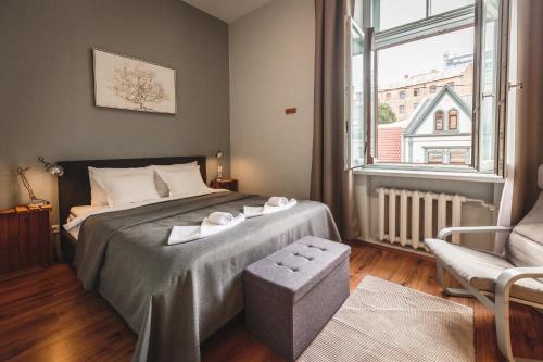 a bedroom with a bed and a chair and a window at Bearsleys Downtown Apartments in Rīga