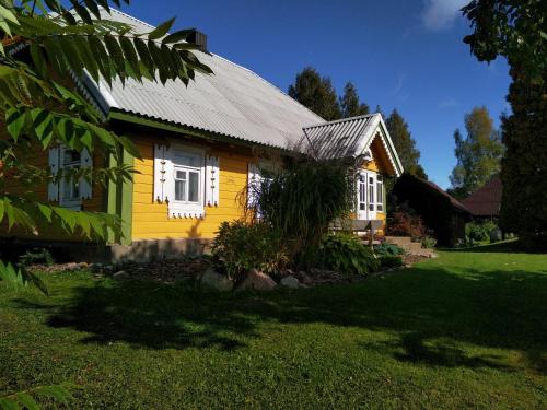 a yellow house with a metal roof at Kačiūniškis in Kaciūniškiai