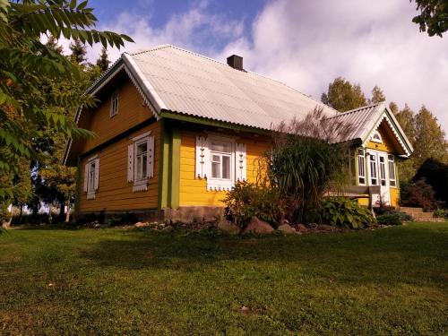a yellow house with a gray roof at Kačiūniškis in Kaciūniškiai