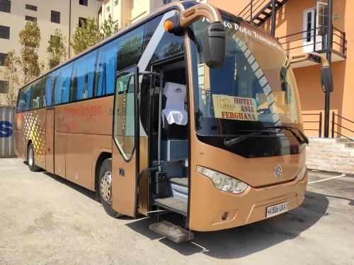 an orange bus parked in a parking lot with its door open at Asia Hotel Fergana in Fergana