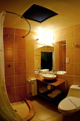 a bathroom with a sink and a toilet and a mirror at Hotel Jardines de Uyuni in Uyuni