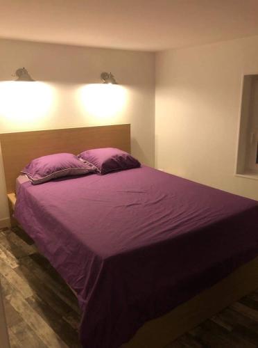 - une chambre avec un lit violet et 2 oreillers dans l'établissement Appartement face au Donjon, à Pons