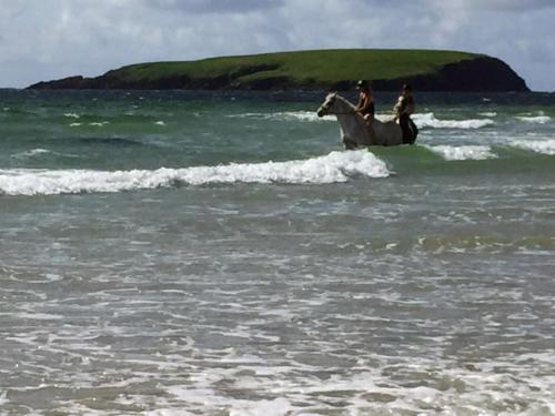 two people riding a horse in the ocean at Creevagh (Room Only) in Keel
