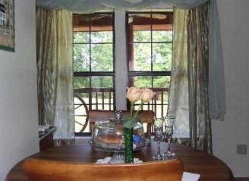 a dining room with a table and two windows at Susan's Cottages in Alexandria