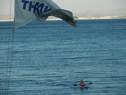a man in a boat in the water with a flag at Theoxenia Chios Apartments in Paralia Agias Foteinis