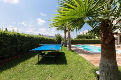 a blue ping pong table next to a palm tree at Aria Villas - Private Pool, Playground, Ping Pong & Close to Beach, By ThinkVilla in Pigi