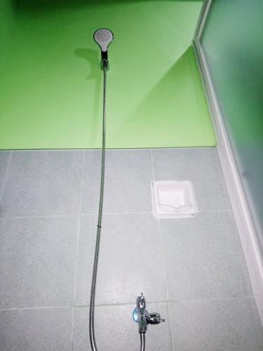 a shower in a bathroom with a hose on the floor at In-N-Out Hostel in Siquijor