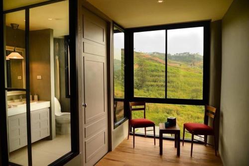 a bathroom with a large window with a view of a hill at Sirinati Khao Kho in Khao Kho