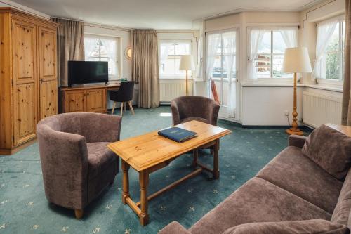 Una sala de estar con una mesa y sillas y un televisor. en Hotel Post, en Nauders