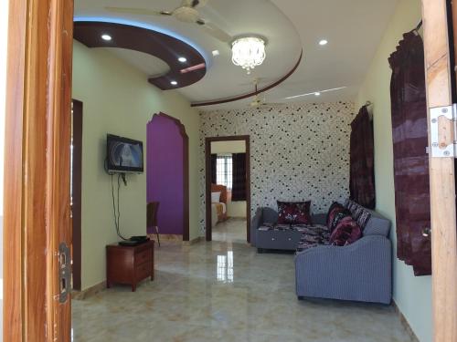 a living room with two couches and a tv at Sushmika Villas in Yercaud