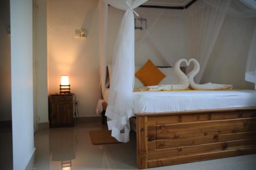 a bedroom with a bed with a white canopy and a lamp at Tranquility guest house in Hikkaduwa