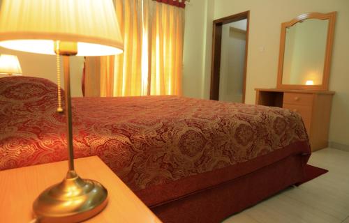 a bedroom with a bed and a lamp on a table at Al Shorouq Hotel Apartments in Muscat