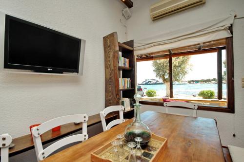 ein Esszimmer mit einem Tisch mit Stühlen und einem TV in der Unterkunft Pallas Pension in Elafonisos