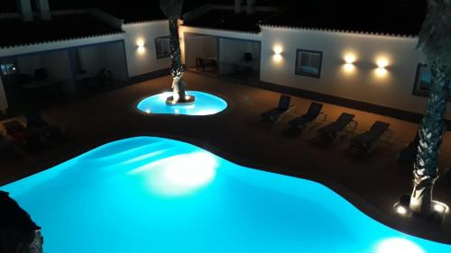 a pool in a room with chairs and lights at Casa Almeida in Vimieiro