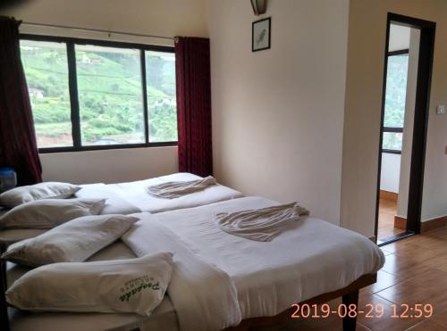 2 aparte bedden in een kamer met een raam bij Poopada in Munnar