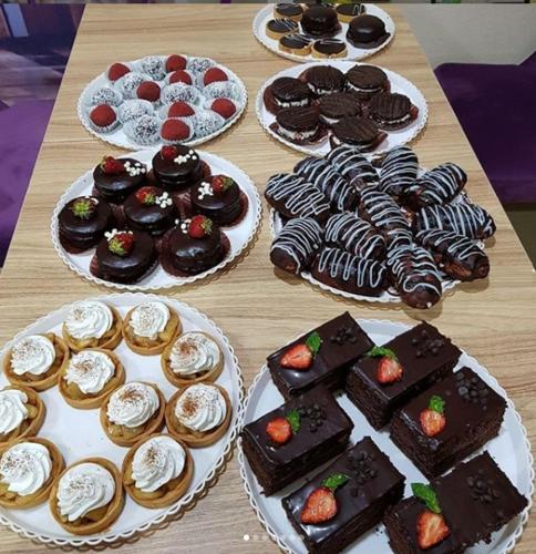 Una mesa llena de diferentes tipos de postres en platos. en GRAND STAR HOTEL, en Qarshi