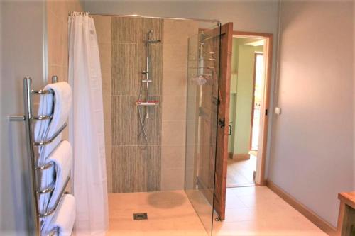 La salle de bains est pourvue d'une douche avec une porte en verre. dans l'établissement Blashford Manor Holiday Cottage - The Dartmoor Cottage, à Ellingham