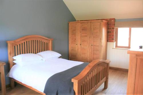 - une chambre avec un lit en bois avec des draps blancs et une fenêtre dans l'établissement Blashford Manor Holiday Cottage - The Dartmoor Cottage, à Ellingham