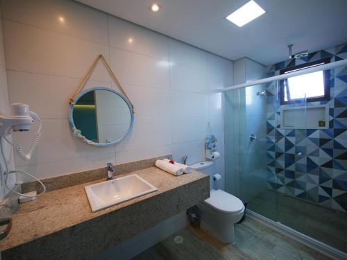 a bathroom with a sink and a toilet and a mirror at Pousada Ecos Beach in Porto De Galinhas