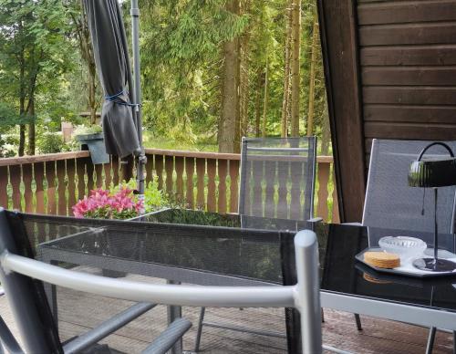einen Glastisch und Stühle auf einer Veranda mit Sonnenschirm in der Unterkunft Wanderhütte Zum Glückstal in Neuhaus am Rennweg