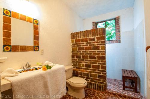 a bathroom with a toilet and a brick wall at Hotel Casa Pomarrosa in Malinalco