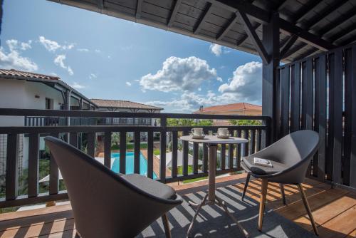 a patio with two chairs and a table on a balcony at L'Anderenis Boutique Hôtel in Andernos-les-Bains
