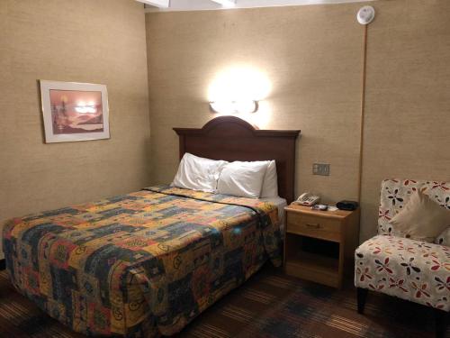 um quarto de hotel com uma cama e uma cadeira em Red Carpet Inn Syracuse Airport em North Syracuse