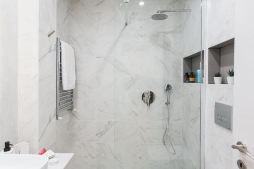 a bathroom with a shower with white marble tiles at Disinffected Kifissia Central near Metro Apartment 1BR in Athens