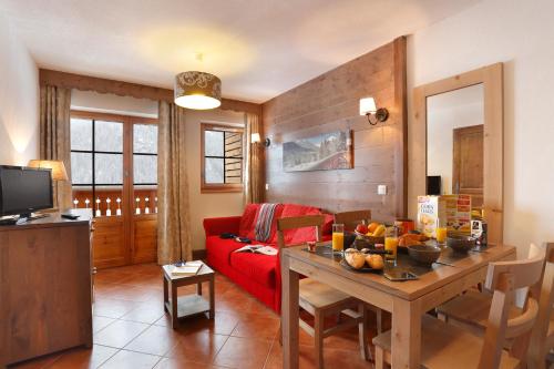 a living room with a red couch and a table at Résidence Néméa Le Grand Lodge in Châtel