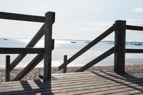 a wooden pathway to the beach with the ocean in the background at L'Anderenis Boutique Hôtel in Andernos-les-Bains
