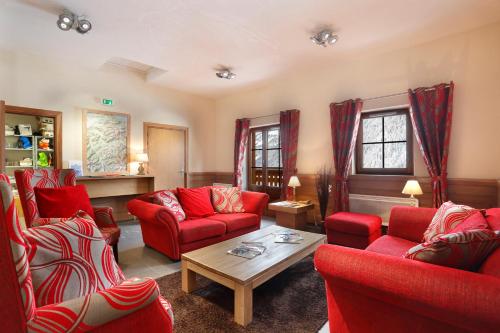 a living room with red couches and a coffee table at Résidence Néméa Le Grand Lodge in Châtel