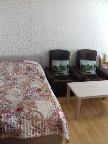 ヴェリーキー・ノヴゴロドにあるTimura Frunze-Olovyanka Apartmentのベッドルーム1室(ベッド1台、椅子2脚、テーブル付)