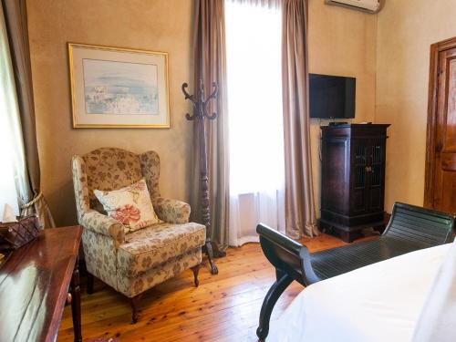 a living room with a chair and a television at Old House Lodge in Beaufort West
