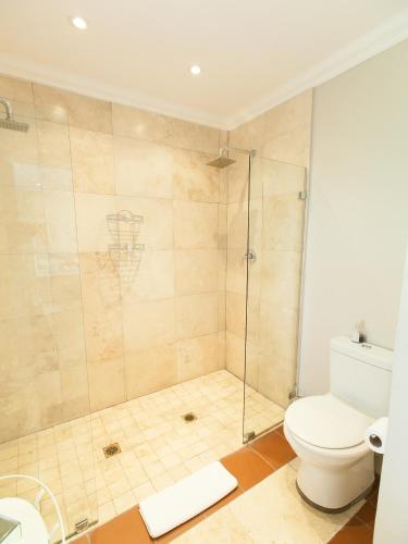 a bathroom with a toilet and a glass shower at Old House Lodge in Beaufort West