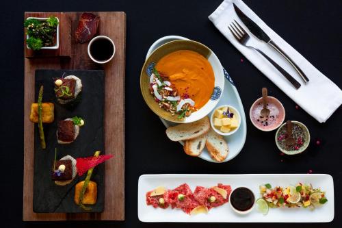 a table with a bowl of soup and a plate of food at De Kombuys in Oudtshoorn