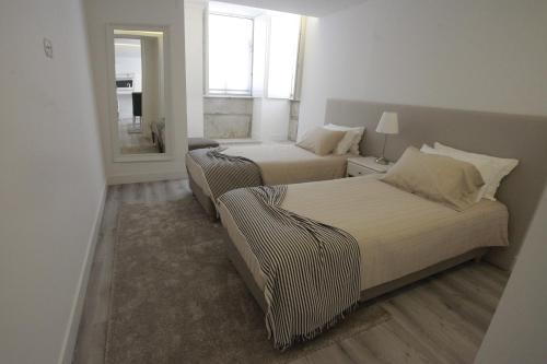 una camera da letto con due letti e uno specchio di Apartamento das Malheiras a Viana do Castelo