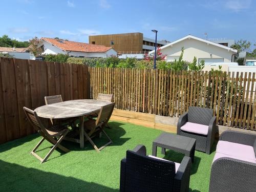 a patio with a table and chairs and a fence at Chambre privée avec terrasse in Capbreton