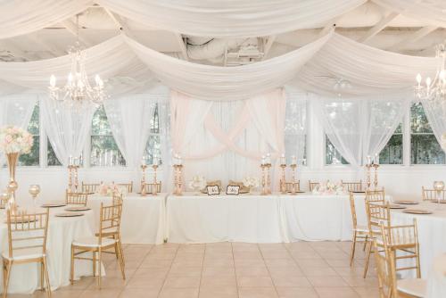 a wedding reception in a white room with tables and chairs at Georgia Palms & Gardens in Powder Springs