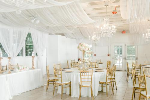 a white room with tables and chairs and chandeliers at Georgia Palms & Gardens in Powder Springs