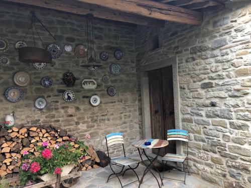 a patio with a table and chairs and a stone wall at La Locanda Della Campanara in Santa Sofia