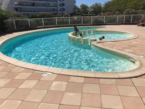 a large pool of blue water in a courtyard at Appartement classé, vue mer, clim, wifi, parking in La Grande-Motte