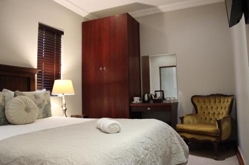 a bedroom with a bed and a chair and a mirror at Abiento Guesthouse in Bloemfontein